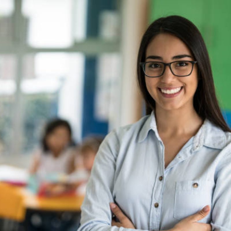 Portrait of a happy Latin American teacher at the school looking at the camera smiling - education concepts